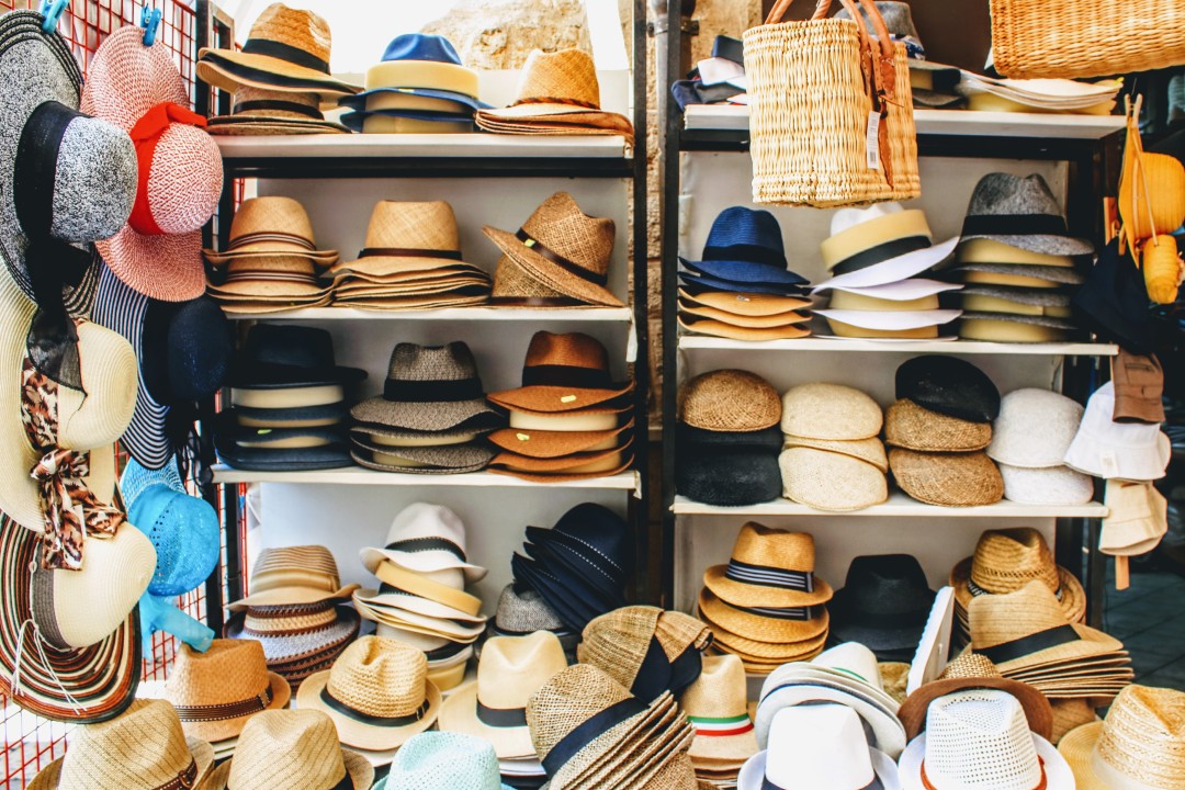 An image of hats on shelves for the "The Hat Shop of Titles & Identity" article